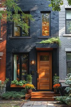 a black house with wooden doors and plants on the front steps, surrounded by greenery