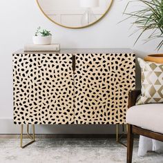 a black and white patterned cabinet next to a chair with a mirror on the wall