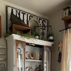 an old china cabinet is decorated with plants and other items in the corner, along with antiques