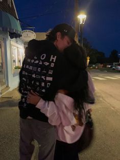 a man and woman hugging on the street at night