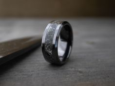 a black and white wedding ring sitting on top of a wooden table next to a knife