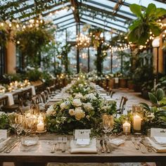 a long table is set with candles and flowers for an elegant wedding reception in a greenhouse