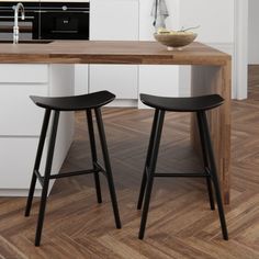 two wooden stools sitting in front of a kitchen counter with a bowl on it