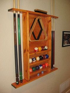 a wooden rack with pool balls, cues and cues hanging on the wall above it