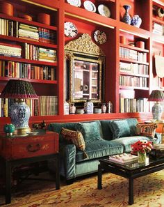 a living room filled with lots of furniture and bookshelves covered in red walls