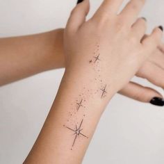 a woman's arm with stars on it and her hand holding the wrist tattoo