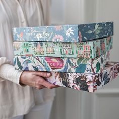 the woman is holding three boxes with designs on them, both in different colors and patterns