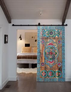 an open door to a bedroom with a bed in the background and artwork on the wall