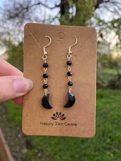 This listing is for one pair of Dainty, Black Onyx Moon Dangle earrings. Please note that the Black Onyx crescent moons are genuine, but the remaining stones are faux. Each pair of earrings are made to order, just for you!  ･ ｡ﾟ☆: *.☽ .* :☆ﾟ. Black onyx is the stone of protection, strength, and willpower. Onyx is an excellent stone in providing one with the ability to pursue their goals and dreams but also protects its wearer along the way. Wearing Onyx provides its wearer with a protective shield, deflecting any negative energy that may come your way.  ･ ｡ﾟ☆: *.☽ .* :☆ﾟ. ☆Care instructions☆ We highly recommend avoiding water and direct sunlight, as prolonged exposure to either can cause the silver and copper to tarnish. ☽Thank you for visiting Happy Zen Gems☆ Black Moon Charm Jewelry For Party, Handmade Black Moon-shaped Earrings, Handmade Black Moon Earrings, Black Jewelry With Moon Charm For Party, Black Crescent Moon Charm Earrings, Black Moon Shaped Earrings For Gift, Black Moon-shaped Earrings For Gift, Black Crescent Earrings For Pierced Ears, Black Moon Phase Earrings