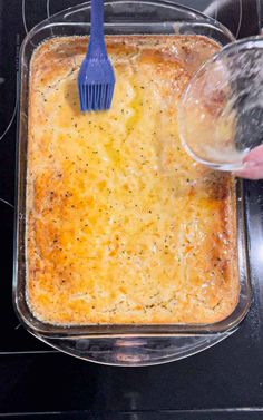 someone using a blue spatula to stir food in a casserole dish