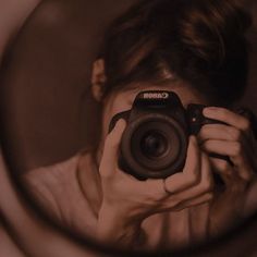 a woman holding a camera up to her face