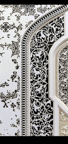 an intricate design on the side of a white and black wall with a window in it