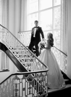 a bride and groom walking down the stairs at their wedding reception in black and white