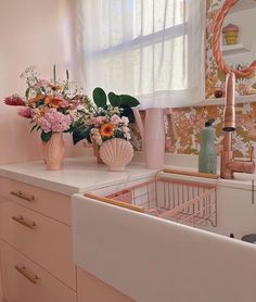 two vases filled with flowers on top of a kitchen counter next to a sink