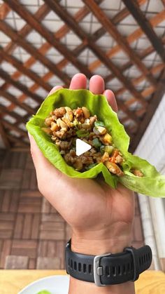 a person holding up a green leaf filled with food