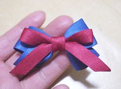 a hand holding a small red and blue bow