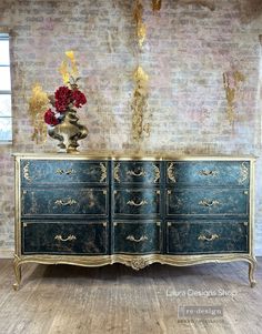 an old dresser with flowers on it in front of a brick wall