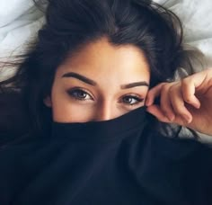 a woman is covering her face with a black scarf over her head and looking at the camera