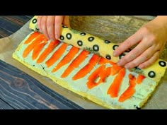 a person is cutting carrots on a piece of paper that has been decorated with black dots