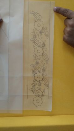 two pieces of paper with designs on them being held up by someone's hand