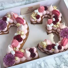 a number shaped cake sitting in a box on top of a marble countertop with flowers and seashells