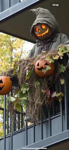 a scarecrow with pumpkins hanging from it's balcony