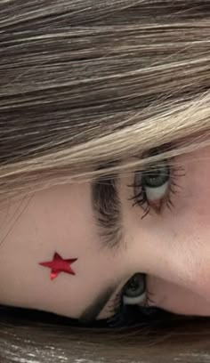 a close up of a person's face with a red star on her forehead