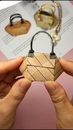 two hands holding a small wooden object in front of a book with other items on it