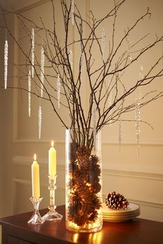 a vase filled with pine cones next to a candle and some candles on a table