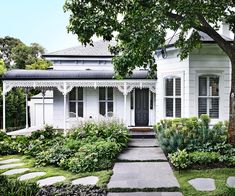 a white house sitting next to a lush green forest