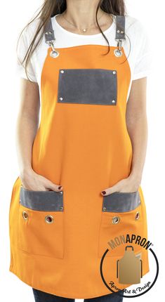 a woman standing with her hands on her hips wearing an orange apron and black pants