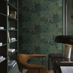 a chair and desk in front of a wallpapered bookcase with books on it