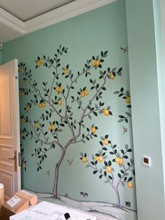 a painted tree with lemons and butterflies on the wall next to a toilet paper dispenser