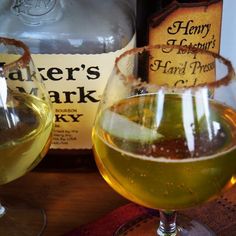 two glasses filled with liquid next to bottles