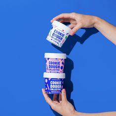 two hands holding three ice creams in front of a blue background with the words cookie dough on it