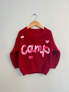 Valentines Custom Knit Sweater! The cutest hand embroidered sweater with a pink multicolor chunky yarn on an red sweater.  Sweaters are an oversized fit. Model is wearing 18-24 months sweater (but typically wears 18 month clothing). Stay true to size for baggy fit that will last even longer!  CARE: wash normal (recommended inside out but not necessary) and lay flat to dry to avoid yarn fuzzing.  For more info, questions, changes or customs- message us on here or on instagram @ campcoveco! Cozy Red Cotton Sweater, Trendy Embroidered Knit Sweater, Cute Oversized Chunky Knit Sweater, Playful Crew Neck Sweater For Fall, Playful Crew Neck Fall Sweater, Cute Chunky Knit Sweater For Fall, Red Chunky Knit Long Sleeve Sweater, Playful Knitted Sweater For Fall, Cute Long Sleeve Chunky Knit Sweater