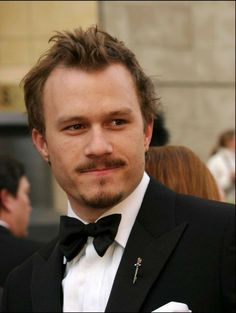 a close up of a person wearing a suit and tie with a moustache