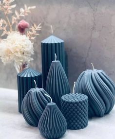 four blue candles sitting on top of a table next to a vase with flowers in it