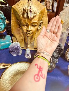 a person's arm with a tattoo on it next to an egyptian statue and other items