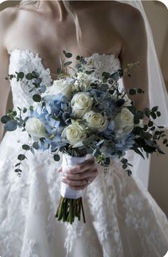 a bride holding a bouquet of white and blue flowers