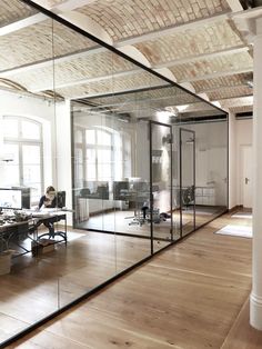 an empty office with glass walls and wooden floors is pictured in this image from the inside