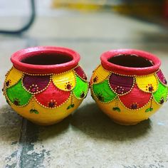 two colorful vases sitting on top of a floor next to each other with designs painted on them