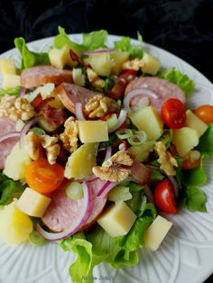 a white plate topped with salad and meat on top of lettuce covered in cheese