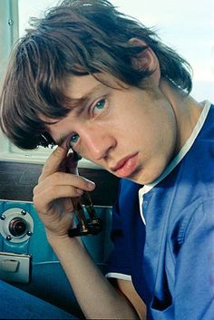 a young man sitting down talking on a cell phone with his hand to his ear