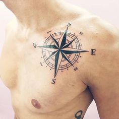 a man's chest with a compass tattoo on his left side and the letter e