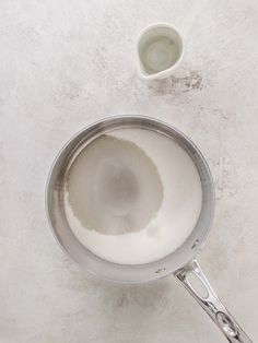 a pan with some white liquid in it next to a small cup on the table