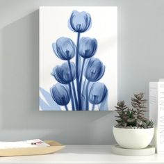 a white shelf topped with a vase filled with blue flowers next to a painting on the wall