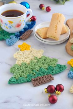 a crocheted christmas tree cookie next to a cup of coffee