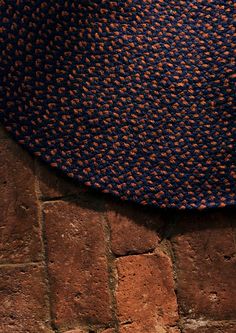 a blue and orange hat sitting on top of a brick floor next to a wall