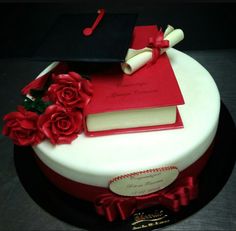 a graduation cake decorated with red roses and a book